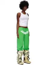 Woman wearing bright green SP5DER classic sweatpants with white logo, casual streetwear style.