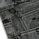 Close-up of Sp5derworlwide denim jeans with black paint splatters and metal rivets.