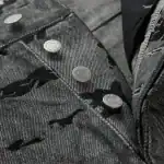 Close-up of Sp5derworlwide denim jeans with unique button design.