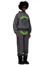 Woman wearing Sp5derworlwide web-themed sweatpants and hoodie, black boots, and sunglasses.